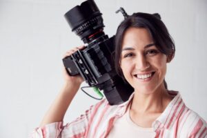 Portrait of female videographer with video camera filming movie in white studio.jpg | ProMedia
