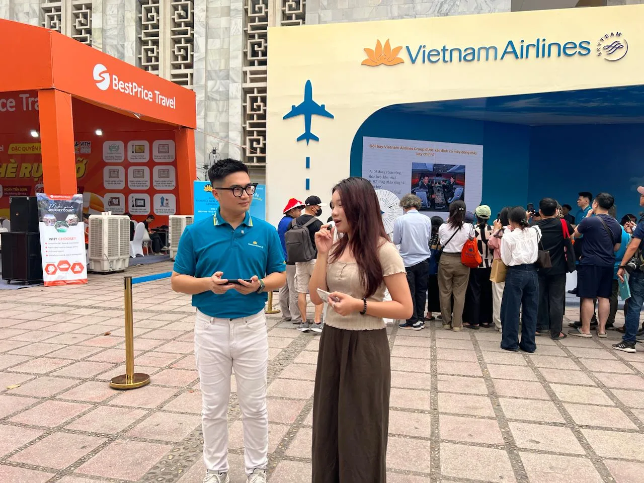 Hai MC nam và nữ của Vietnam Airlines đang trò chuyện, chuẩn bị cho buổi livestream Vietnam Airlines tại triển lãm.