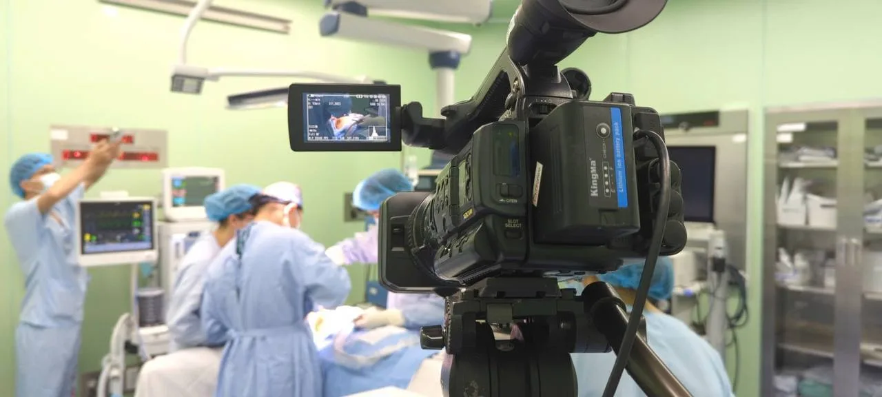 Một camera chuyên dụng đang quay cảnh phẫu thuật trong phòng mổ, livestream hội thảo y tế.