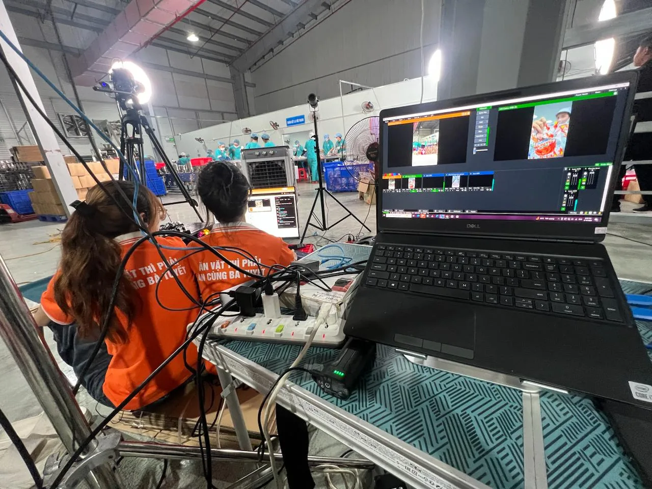 Ekip ProMedia điều khiển livestream với laptop và nhiều dây cáp tại nhà xưởng