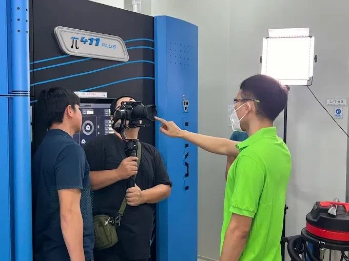 Cameraman and factory engineer filming CNC machine